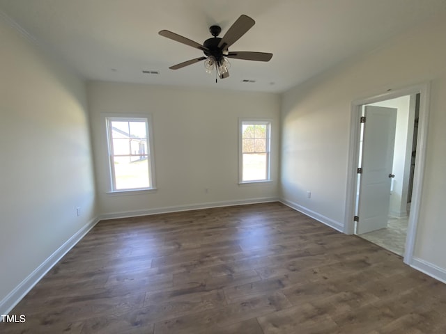 unfurnished room with dark wood-style flooring, visible vents, and baseboards