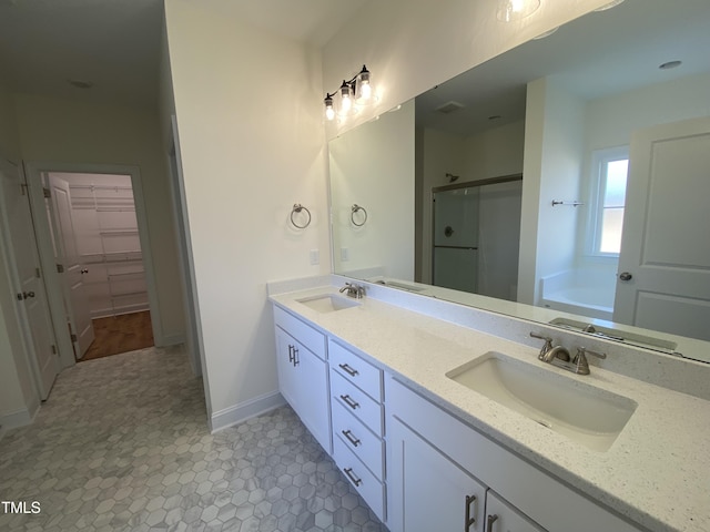 bathroom featuring a bath, a shower stall, double vanity, and a sink