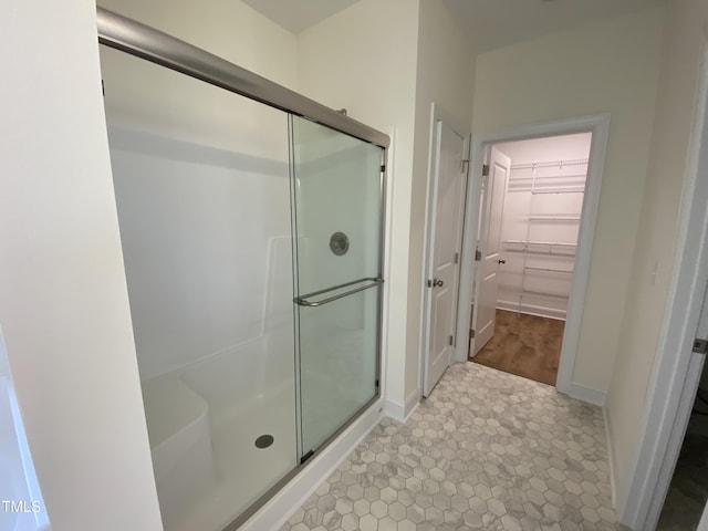 full bathroom with baseboards, a spacious closet, a stall shower, and tile patterned floors