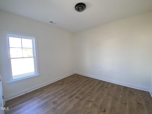 spare room featuring dark wood-style floors, visible vents, and baseboards