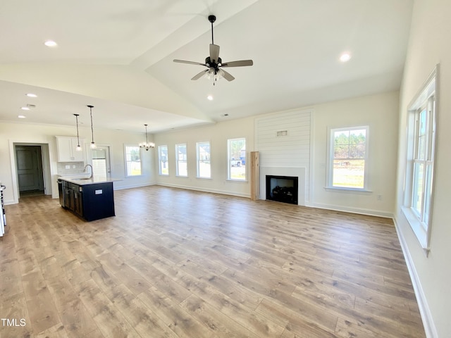 unfurnished living room featuring a fireplace, light wood-style floors, a sink, and vaulted ceiling with beams