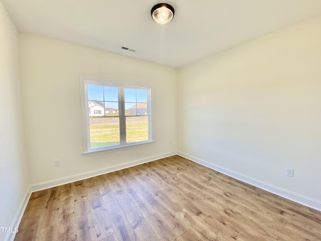 unfurnished room with wood finished floors, baseboards, and visible vents