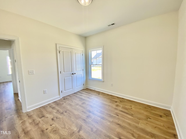 unfurnished bedroom with light wood-style floors, visible vents, baseboards, and a closet