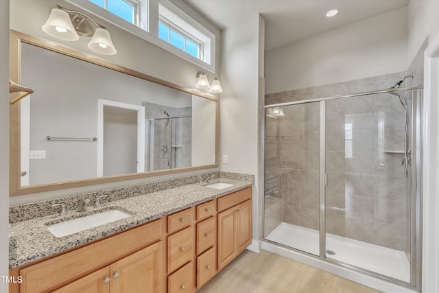 bathroom with hardwood / wood-style floors, vanity, and a shower with shower door