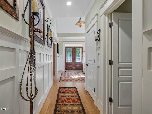 doorway featuring crown molding, french doors, and light wood-type flooring