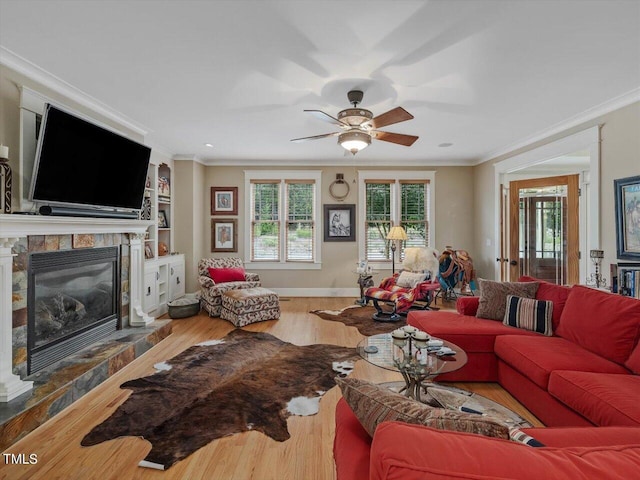 living room with a stone fireplace, crown molding, and hardwood / wood-style flooring