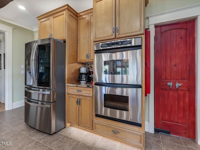 kitchen with dark tile patterned floors, ornamental molding, and appliances with stainless steel finishes