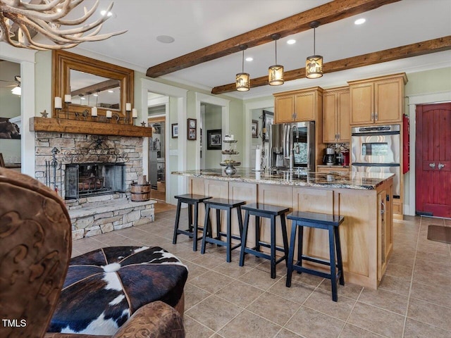 kitchen with beam ceiling, appliances with stainless steel finishes, stone countertops, a fireplace, and decorative light fixtures