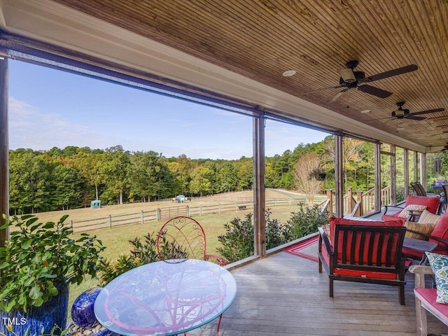 sunroom / solarium featuring ceiling fan, wooden ceiling, and a rural view