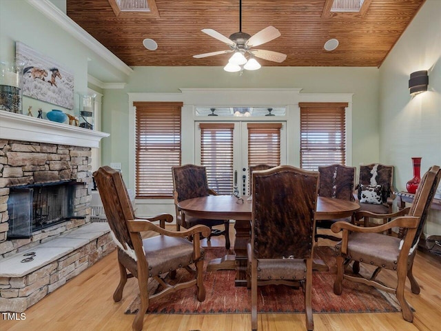 dining area with light hardwood / wood-style flooring, wood ceiling, a fireplace, and ceiling fan