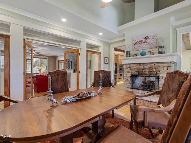 dining area featuring ornamental molding, a fireplace, light wood-type flooring, and ceiling fan