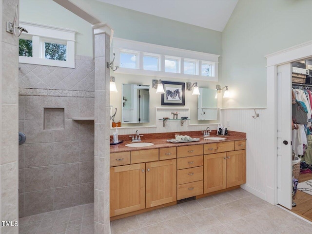 bathroom with vanity, tiled shower, vaulted ceiling, and a wealth of natural light