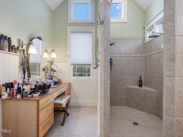 bathroom with vanity, a tile shower, tile patterned floors, and lofted ceiling