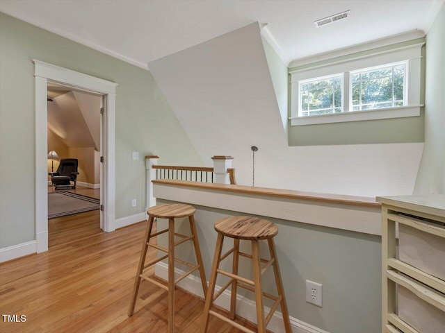 interior space featuring light hardwood / wood-style floors, lofted ceiling, and a kitchen breakfast bar