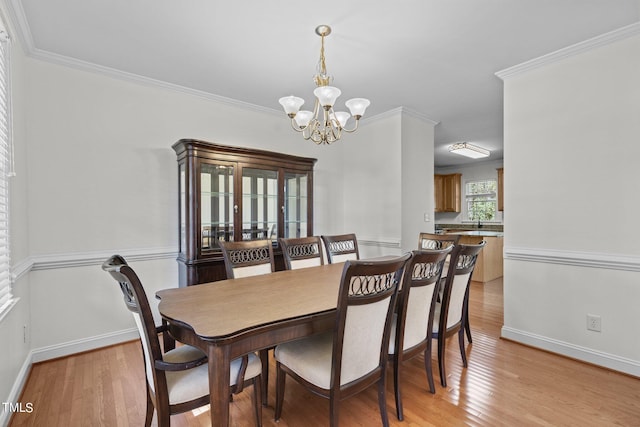 dining room with an inviting chandelier, light hardwood / wood-style flooring, and ornamental molding