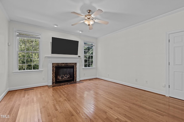 unfurnished living room featuring light wood-type flooring, a high end fireplace, and plenty of natural light