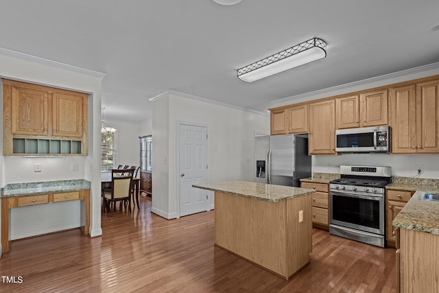 kitchen with ornamental molding, a chandelier, stainless steel appliances, a center island, and hardwood / wood-style floors