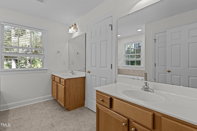 bathroom with tile patterned flooring, a tub to relax in, vanity, and a healthy amount of sunlight