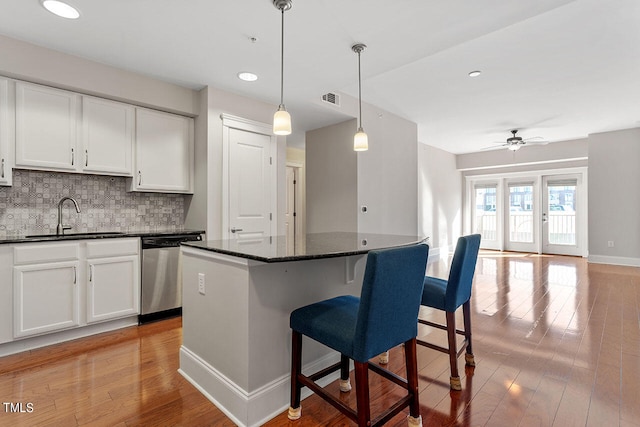 kitchen with sink, light hardwood / wood-style floors, white cabinetry, and dishwasher