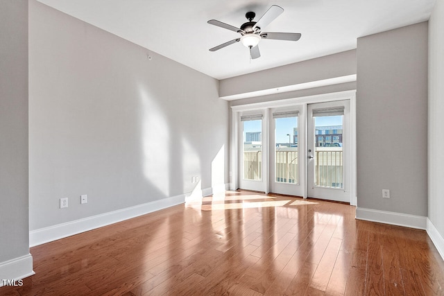 empty room with french doors, ceiling fan, and hardwood / wood-style flooring