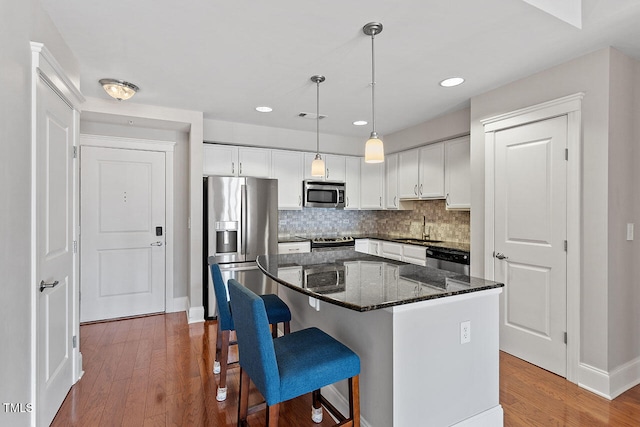 kitchen featuring sink, dark stone countertops, white cabinets, a center island, and stainless steel appliances