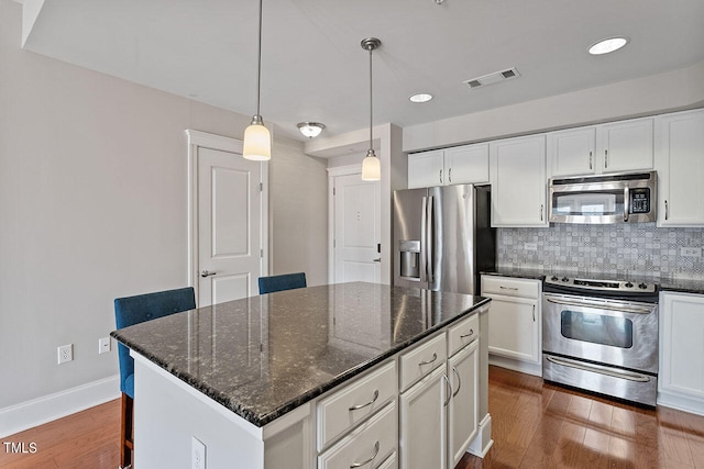 kitchen with a kitchen island, pendant lighting, white cabinets, dark stone counters, and stainless steel appliances