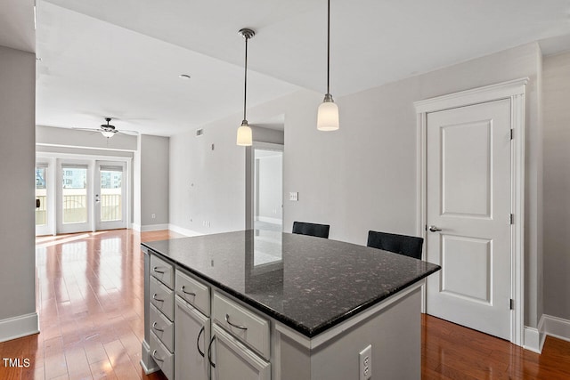 kitchen with dark hardwood / wood-style flooring, hanging light fixtures, a center island, and dark stone counters