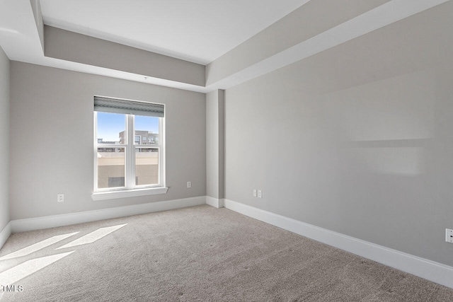 carpeted spare room with a tray ceiling