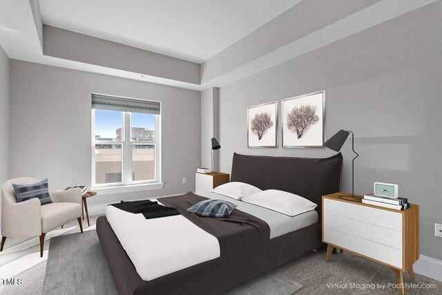 carpeted bedroom with baseboards and a raised ceiling