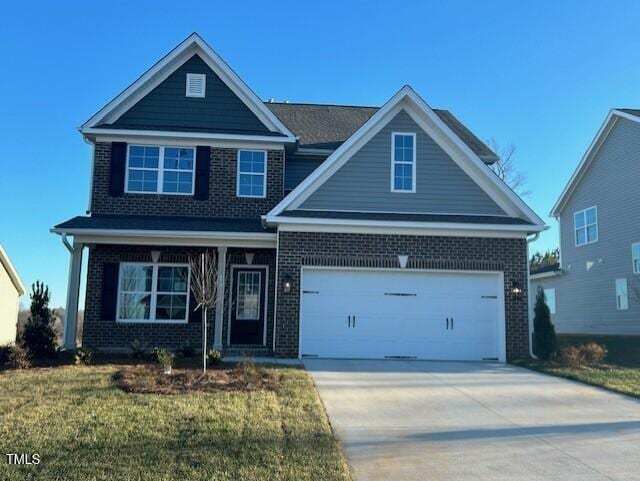 craftsman house with driveway, a garage, a front yard, and brick siding