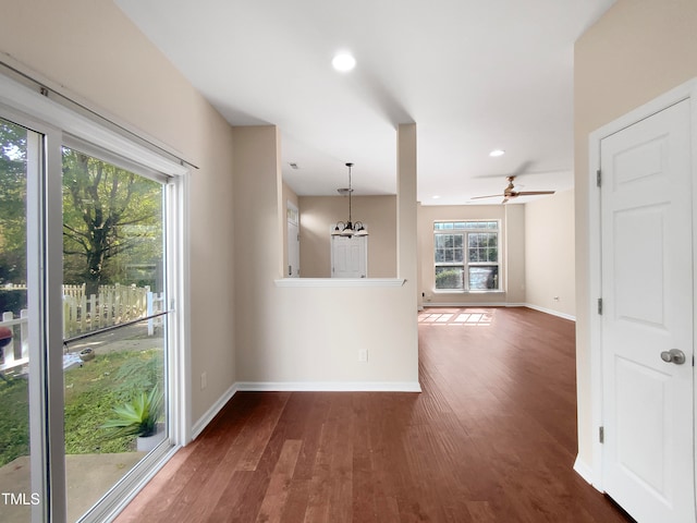 empty room featuring ceiling fan with notable chandelier and dark hardwood / wood-style floors