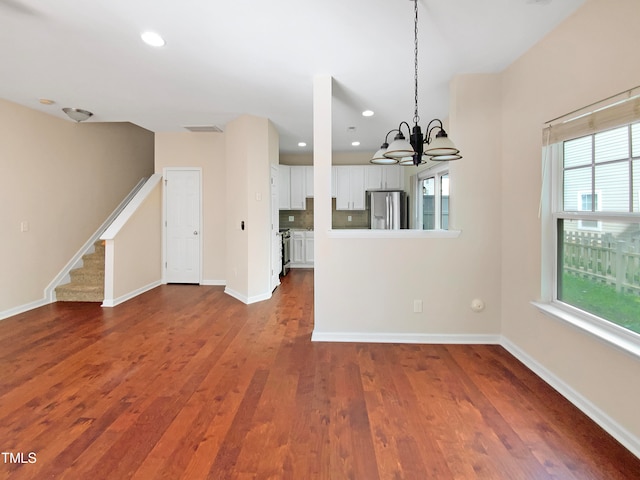 unfurnished dining area with a notable chandelier and dark hardwood / wood-style flooring