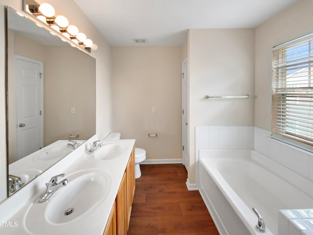 bathroom with a bath, hardwood / wood-style floors, vanity, and toilet