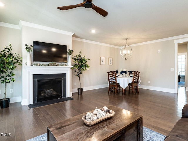 living room featuring dark wood-type flooring, ceiling fan with notable chandelier, and ornamental molding