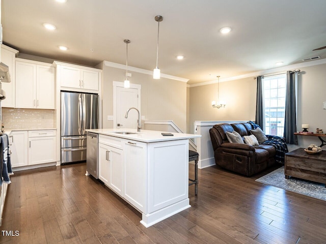 kitchen featuring stainless steel appliances, a center island with sink, sink, and white cabinetry