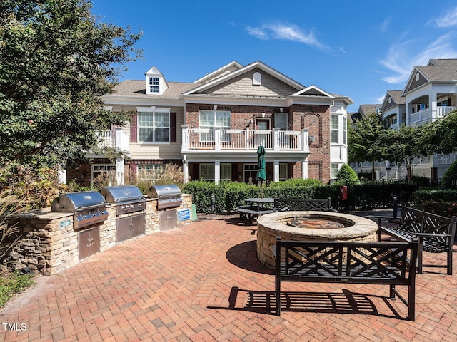 view of patio / terrace featuring a fire pit, a balcony, a grill, and exterior kitchen