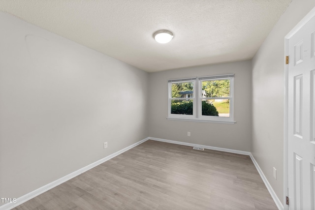 spare room featuring a textured ceiling and light hardwood / wood-style floors