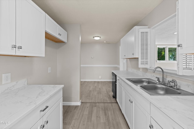 kitchen with light stone countertops, light hardwood / wood-style floors, white cabinets, and sink