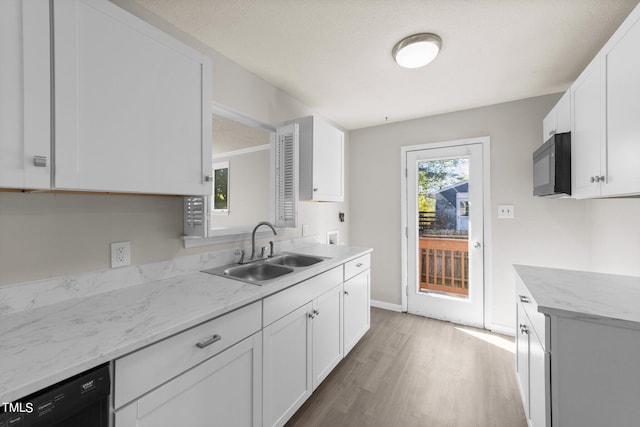 kitchen with light wood-type flooring, light stone counters, black appliances, sink, and white cabinetry