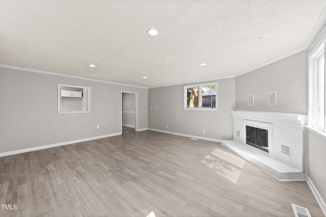 unfurnished living room with a brick fireplace, light wood-type flooring, and a wealth of natural light