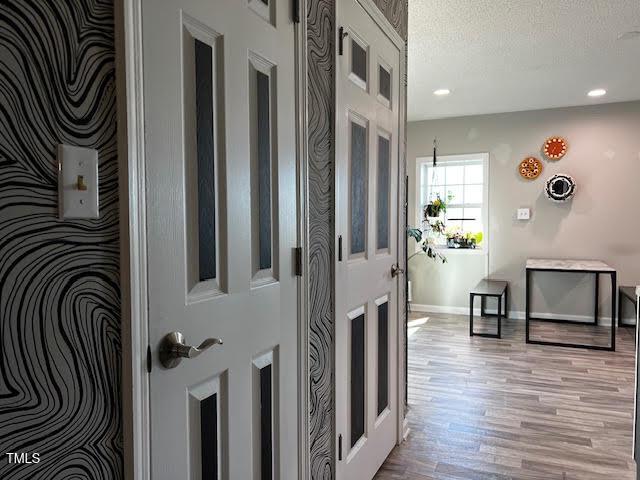 hall featuring light wood-type flooring and a textured ceiling