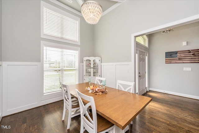 dining area featuring a towering ceiling, a chandelier, and dark hardwood / wood-style flooring