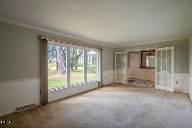 unfurnished room featuring french doors, light colored carpet, a textured ceiling, and ornamental molding