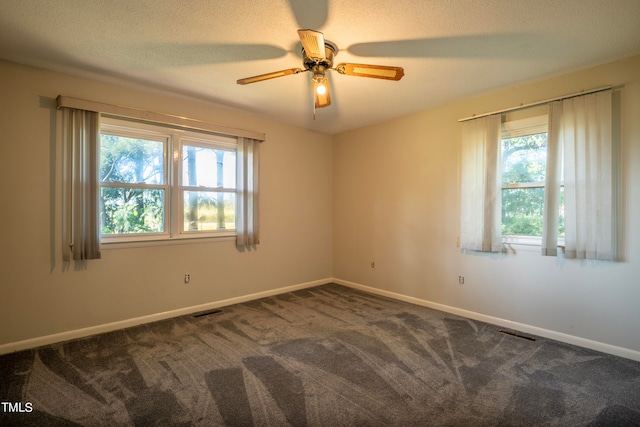 unfurnished room featuring ceiling fan, a textured ceiling, and dark carpet