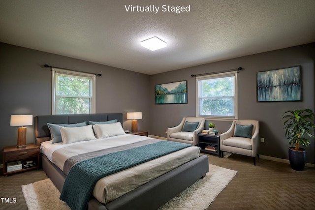 bedroom featuring dark carpet, a textured ceiling, and multiple windows