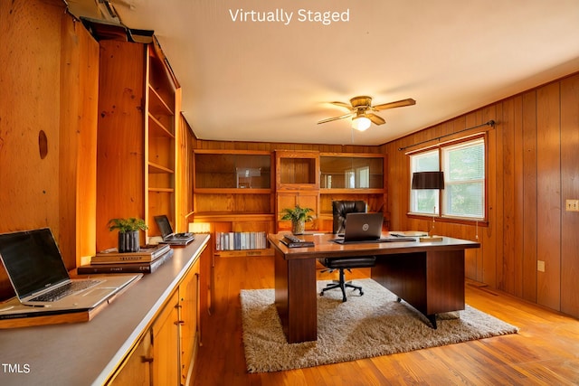 office space featuring light wood-type flooring, wooden walls, and ceiling fan