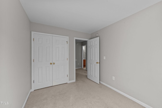 unfurnished bedroom with light colored carpet and a closet