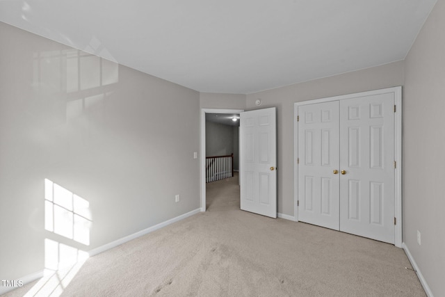 unfurnished bedroom featuring light colored carpet and a closet