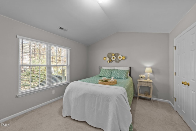 bedroom featuring light colored carpet, lofted ceiling, and multiple windows