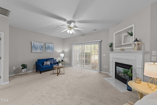 living room featuring ceiling fan, light carpet, and a tile fireplace